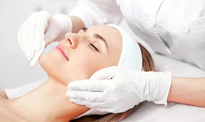 Professional young cosmetologist is curing female skin
