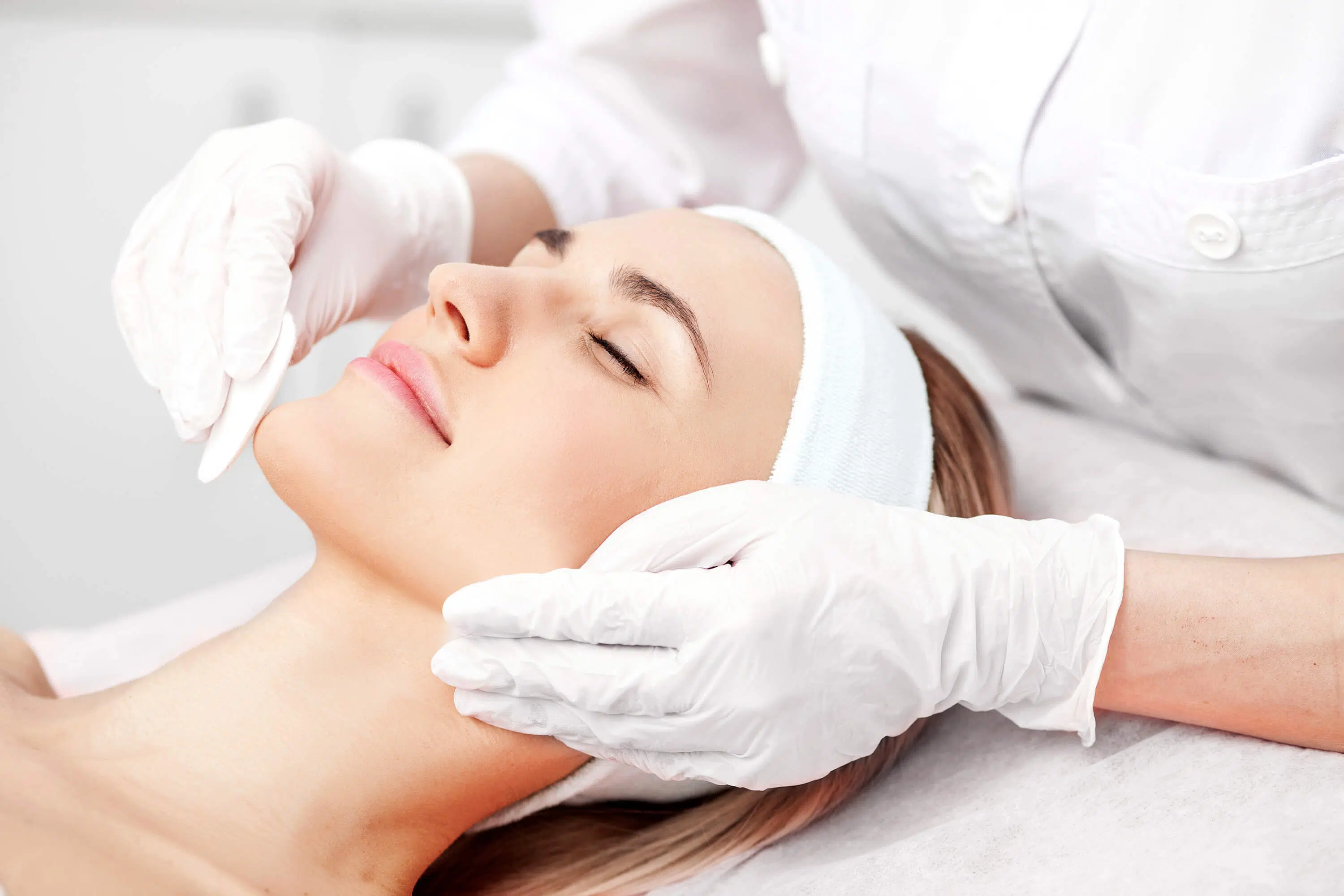 Professional young cosmetologist is curing female skin